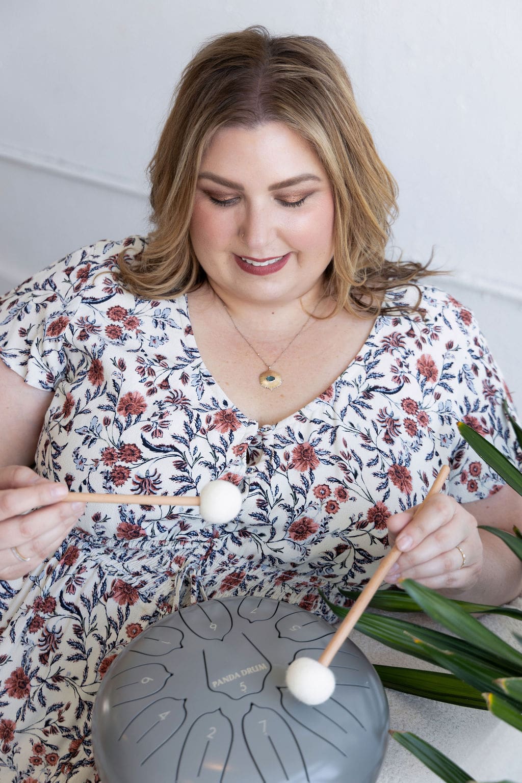 Therapist coach and mentor sitting on a couch holding and playing a somatic healing drum