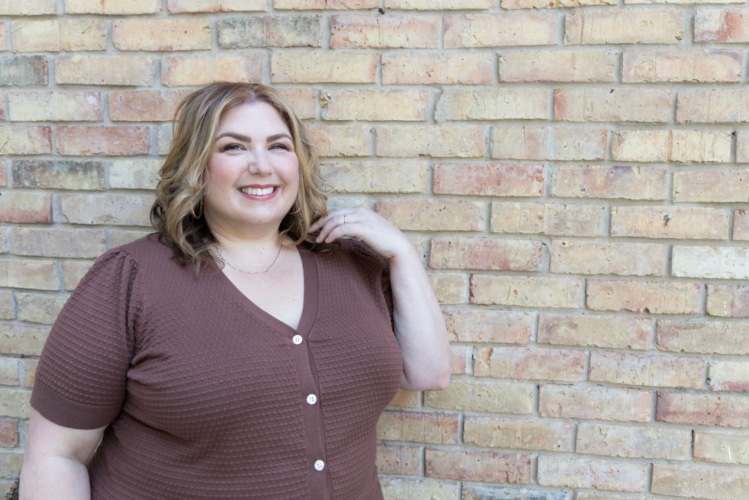 The Empowered Therapist, a coaching mentor for therapists, standing in front of a brick wall, smiling off into the distance