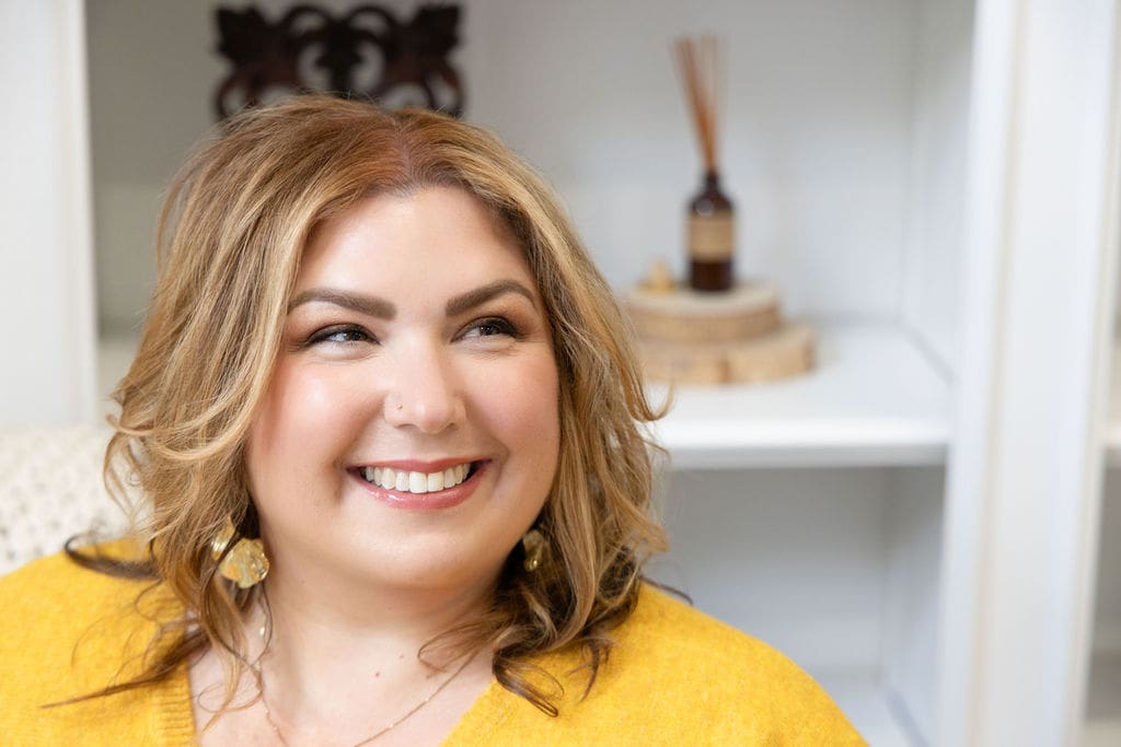 Close-up photo of somatic experiencing practitioner and empowered therapist wearing a yellow shirt and smiling off into the distance