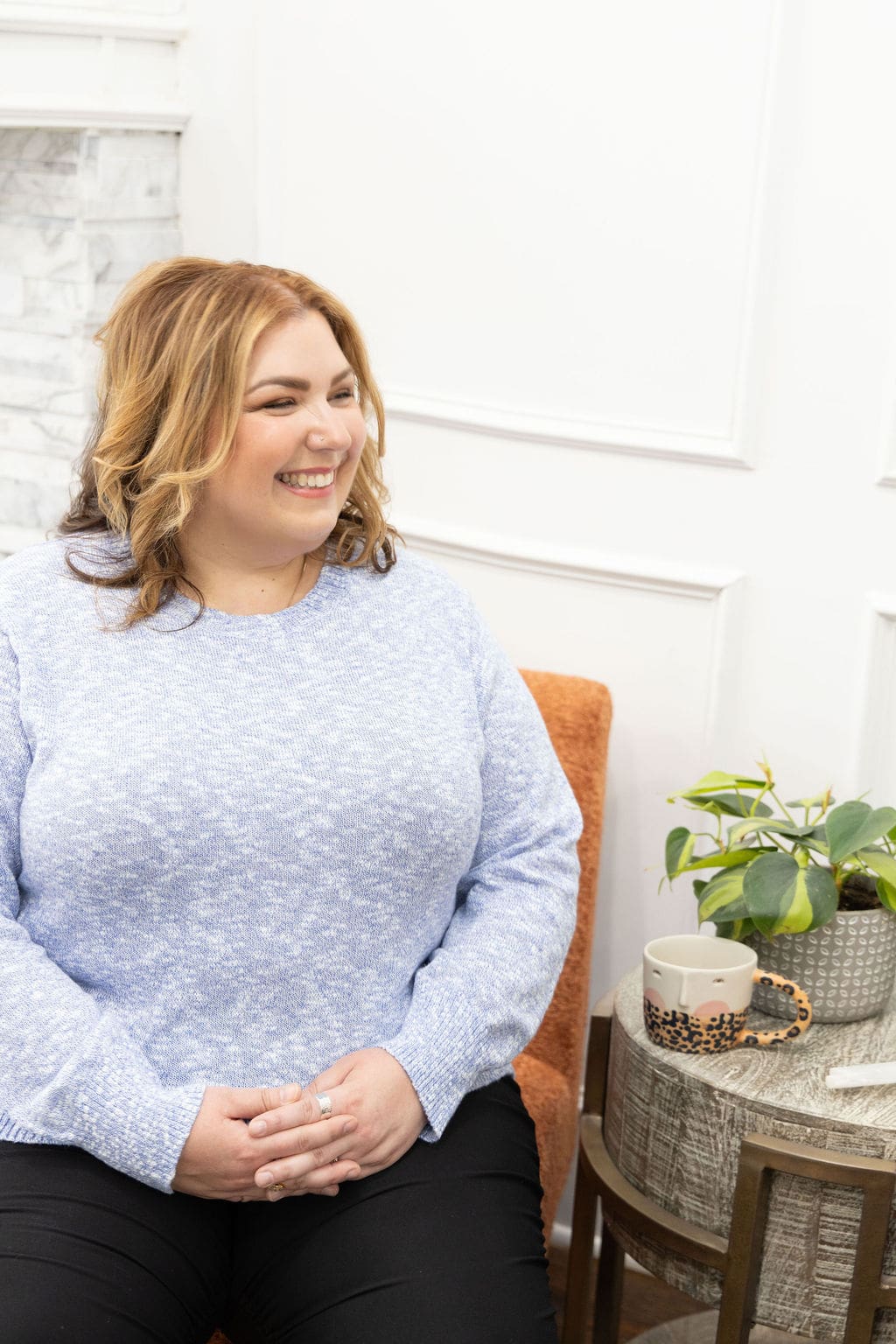Somatic experiencing practitioner and therapist mentor in a blue shirt, sitting in a chair smiling off into the distance