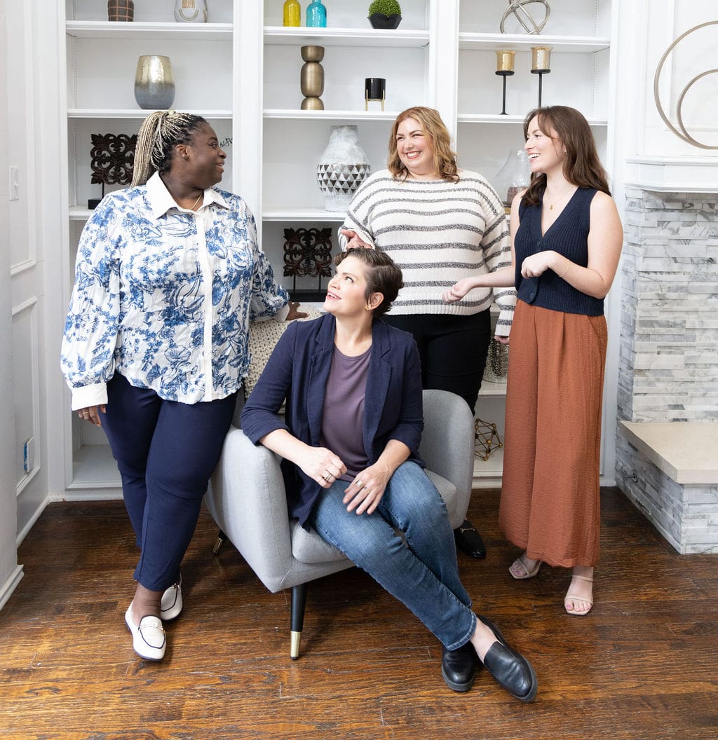 The Empowered Therapist standing in front of a bookshelf laughing and smiling in conversation with a seated somatic experiencing practitioner and two other standing therapists