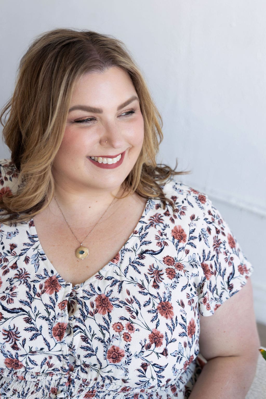 The Empowered Therapist sitting on a couch in a floral dress, smiling off into the distance.