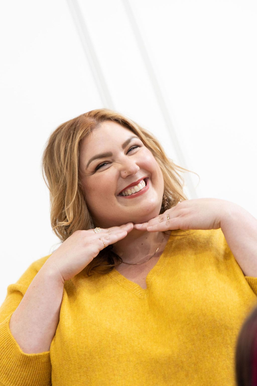 The empowered therapist and therapist mentor wearing a yellow shirt, with hands under her chin smiling at the camera